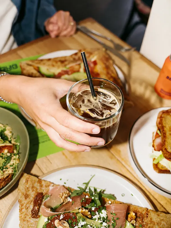 Iced coffee and sharing plates at a Benny and Brew table