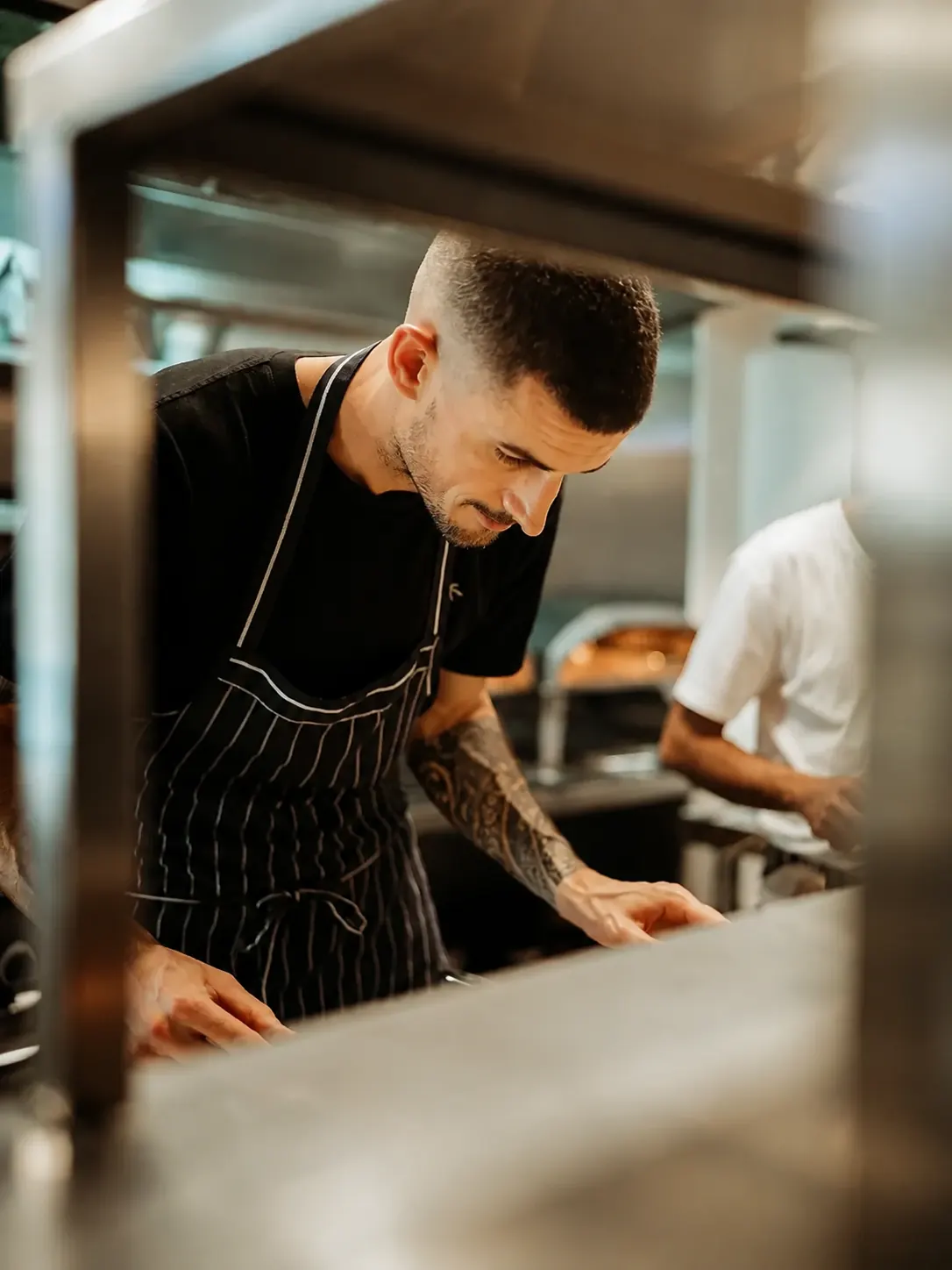 A cook working at the Benny and Brew kitchen pass