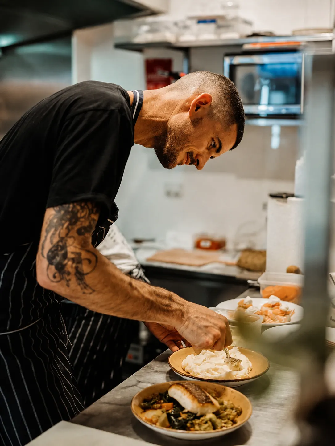 A cook adding the finishing touches to a plate at Benny and Brew